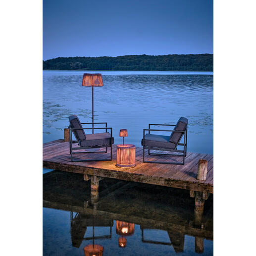 Outdoor-Tisch mit LED-Beleuchtung am Wasser, umgeben von Stühlen.