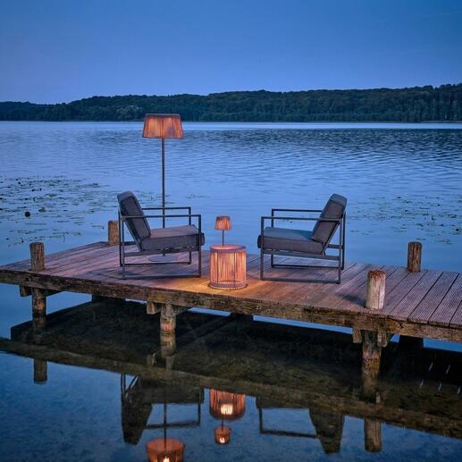 Outdoor-Tisch mit LED-Beleuchtung am Wasser, umgeben von Stühlen.