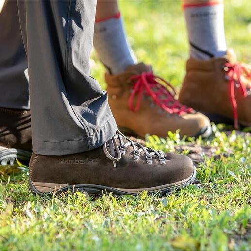 Zamberlan® Wanderstiefel, Füße einer Person in brauner und einer in beiger Stiefel auf einer Wiese.
