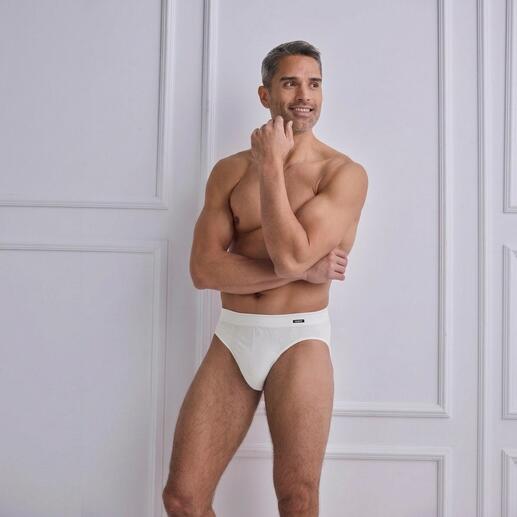 Mann in weißem Cult-Slip zeigt muskulöse Pose.