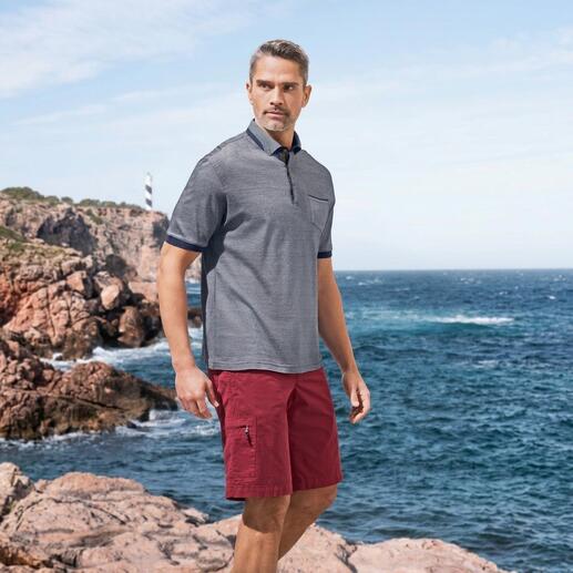 Mann trägt Poloshirt und Bermudas in rot, am Strand.