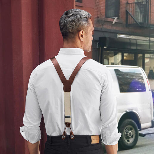 Mann mit Lederhosenträgern und weißem Hemd von hinten in der Stadt.