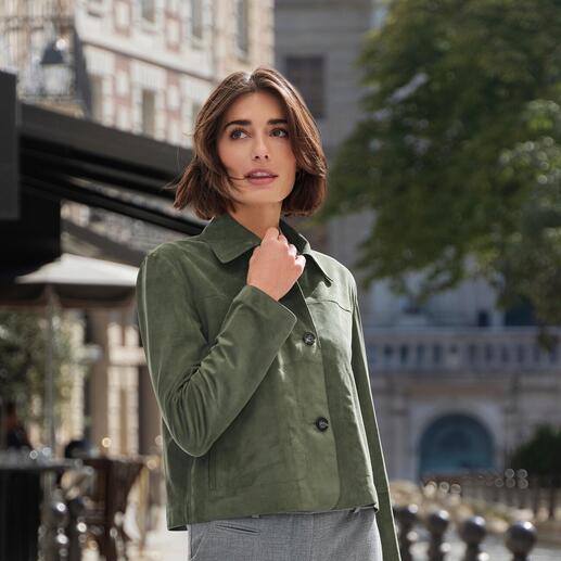 Dame in grüner Lederjacke mit Jeans in einem urbanen Umfeld