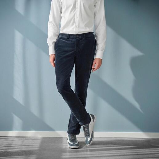 Mann trägt schwarze Samt-Hose, seitliche Ansicht vor einem blauen Hintergrund.