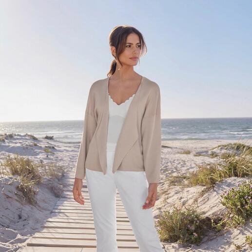 Frau trägt einen Wasserfall-Cardigan am Strand, Sonne scheint.