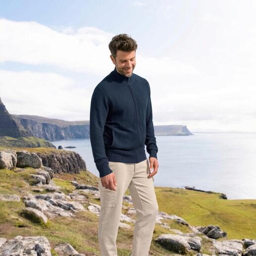Mann trägt einen navyfarbenen Seiden-Klima-Cardigan, stehend vor einer Küstenlandschaft.
