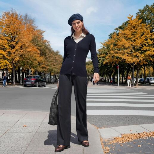 Frau in dunkelblauer Strickjacke und schwarzer Hose in herbstlicher Umgebung.