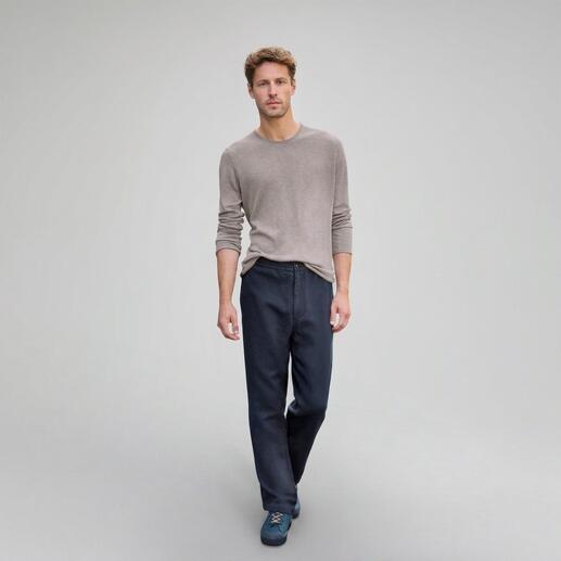 Mann in beiger Bluse und Navy-Hose auf grauem Hintergrund