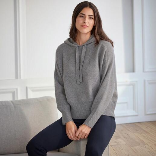Frau sitzt in grauem Boiled Cashmere D-Hoodie auf einem Sessel