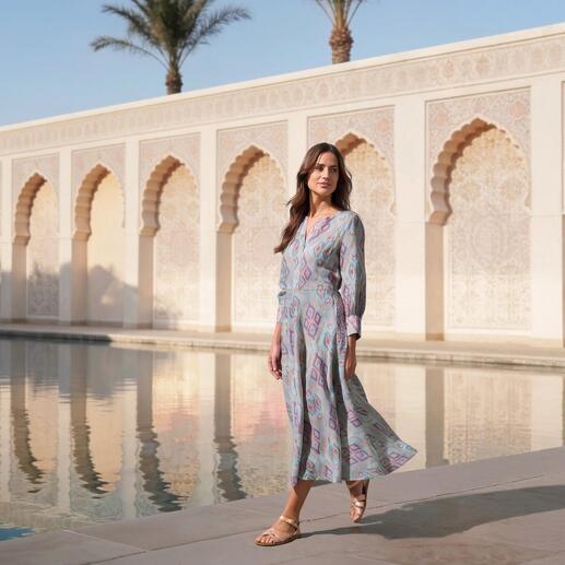 Frau in farbigem Ikat-Kleid neben einem Pool im Freien.