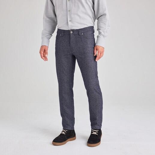 Mann mit grauem Hemd und Woll-Jeans steht auf einem hellen Hintergrund