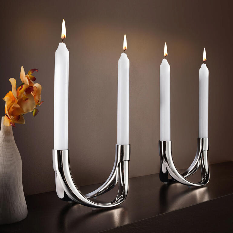Kerzenhalter Bow für 4 Kerzen mit eleganter, geschwungener Metallbasis und brennenden Kerzen.