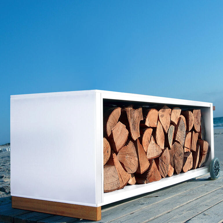Die klare Form und die hochwertigen Materialien machen dieses Design-Highlight zum attraktiven Blickfang – drinnen und draußen. Kaminholzwagen in weißen und naturfarben Holz mit Holz gestapelt.