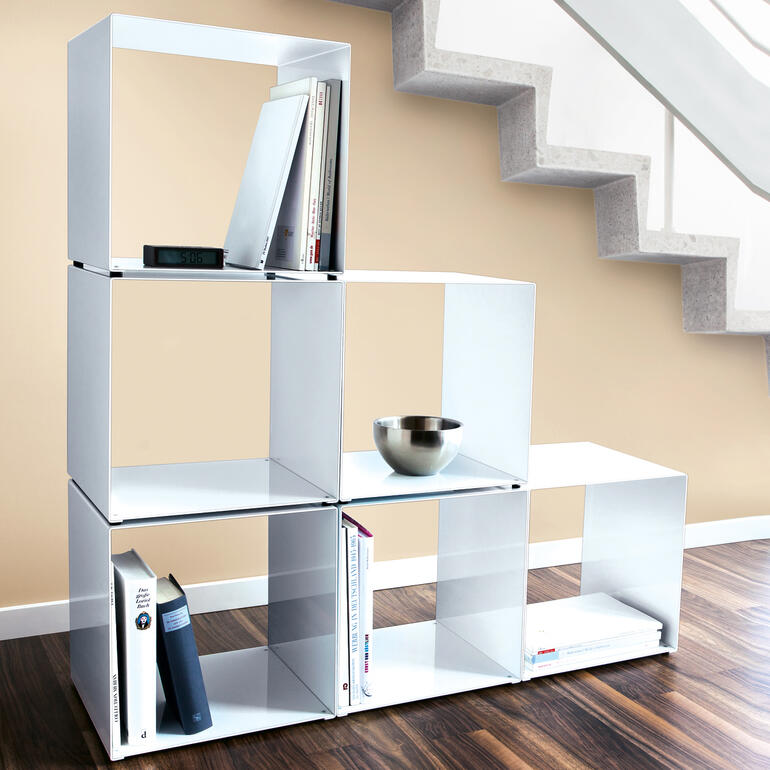 Auch unter Treppen schaffen Sie schnell perfekten Stauraum. Designer-Kubus als Regal mit Büchern und einer Schüssel.