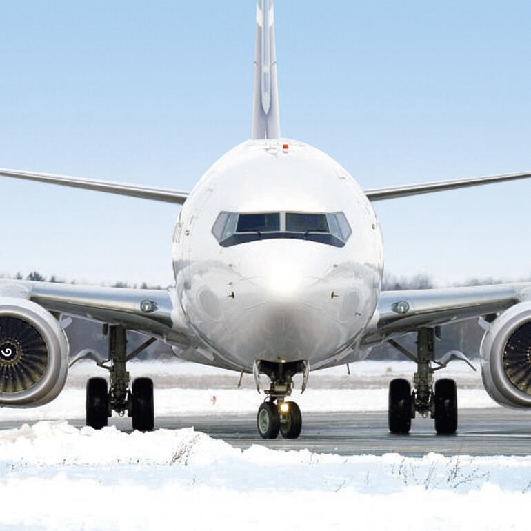 Die Profis nutzen Taugranulat aus Calciumchlorid in Wasser gelöst – als hochwirksamen Flüssig-Enteiser. Flughafen-Szene mit einem Flugzeug im Schnee