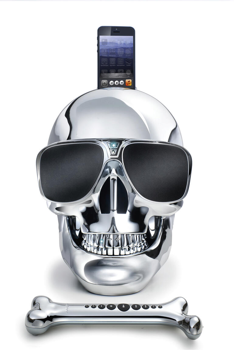 Chromfarbener Schädel-Lautsprecher mit Sonnenbrille und Mobiltelefon.