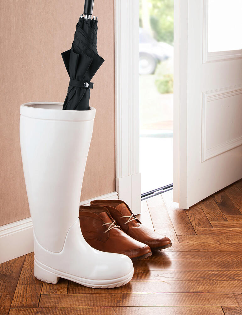Stiefel als Schirmständer mit einem Regenschirm.