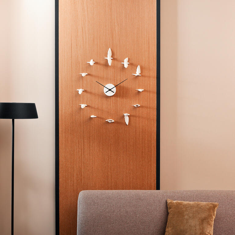 Schwalbenuhr an einer Holzwand über einem Sofa.