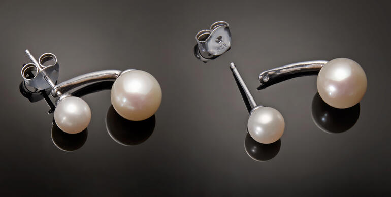 2-in-1 Ohrringe mit schwebenden Perlen in Silber, auf schwarzem Hintergrund.