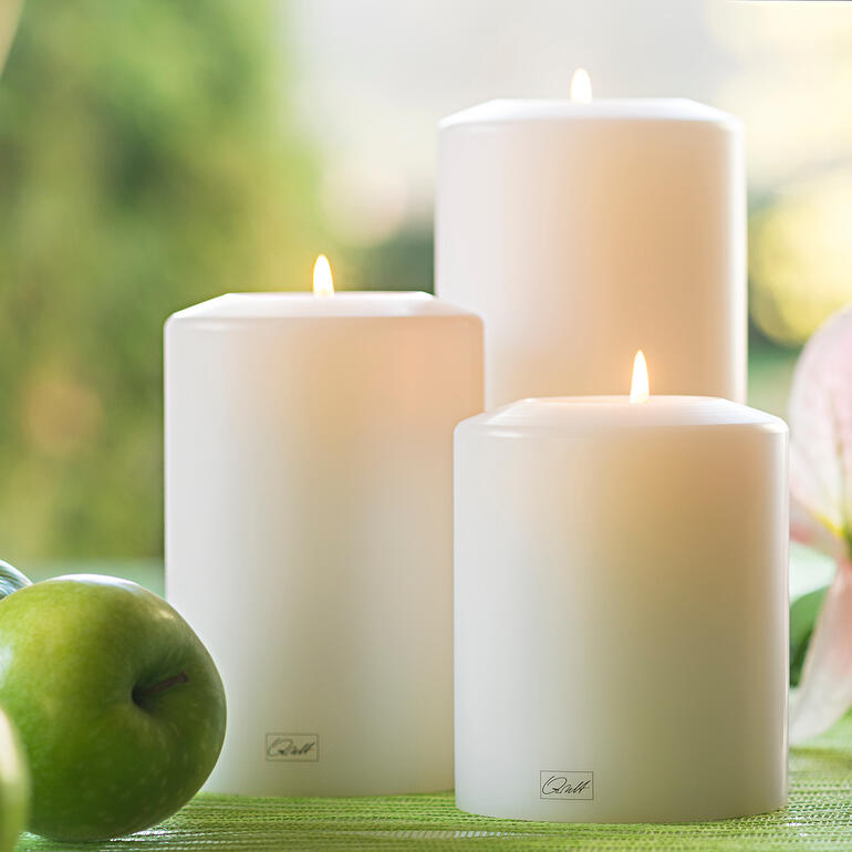 Farluce-Dauerkerze Drei weiße Dauerkerzen in der Natur zwischen Äpfeln und Blumen