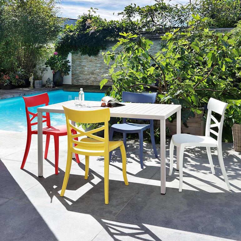 Wohnlicher als die üblichen, oft langweiligen Draußen-Stühle. Bunte Design-Stühle im Freien um einen Tisch herum.