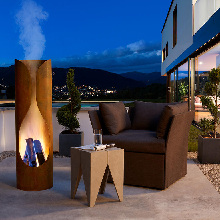 Kamin mit Feuer bei Nacht, gemütlicher Sitzbereich.