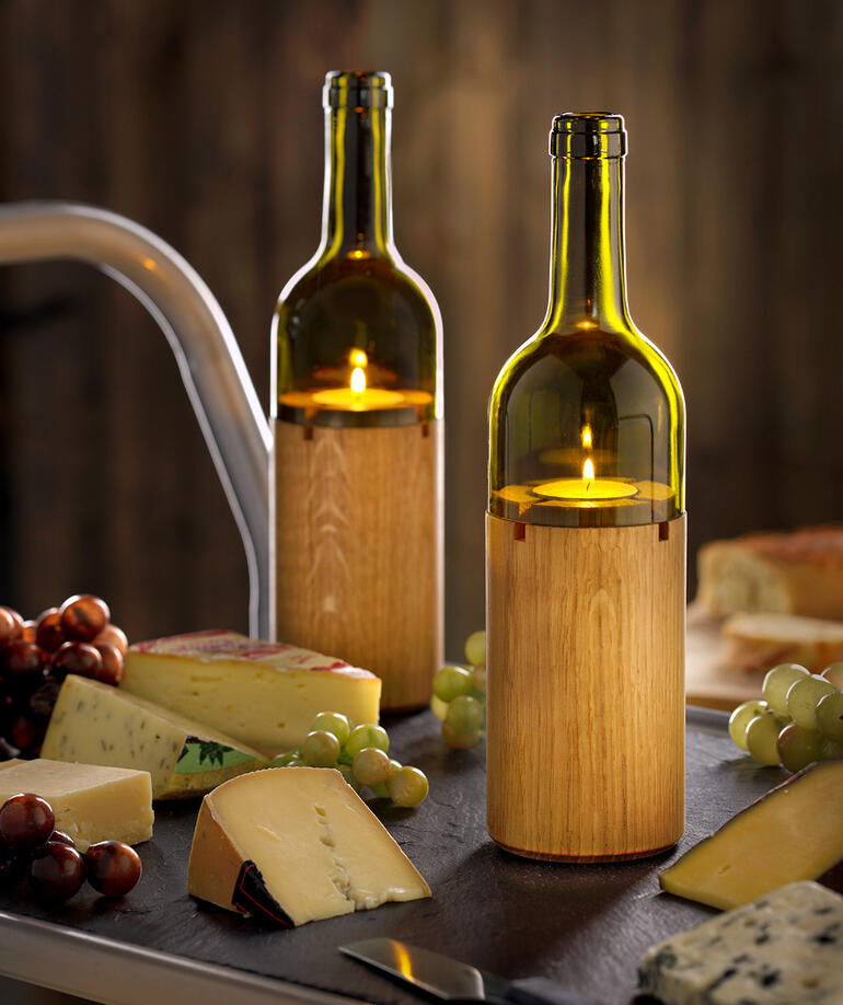 Zwei Weinlichter auf einem Tisch mit Käse und Trauben.