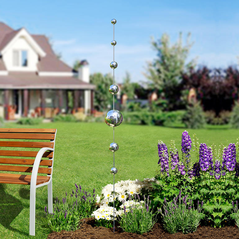 Garten mit kugelartigen Stäben zwischen Blumen.