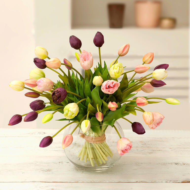 Bunter Tulpenstrauß in einem Glasvasenarrangement.