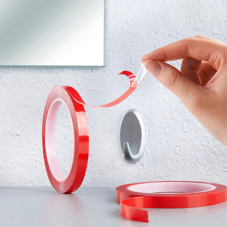 Hand, die rotes Power Tape von der Rolle abzieht.