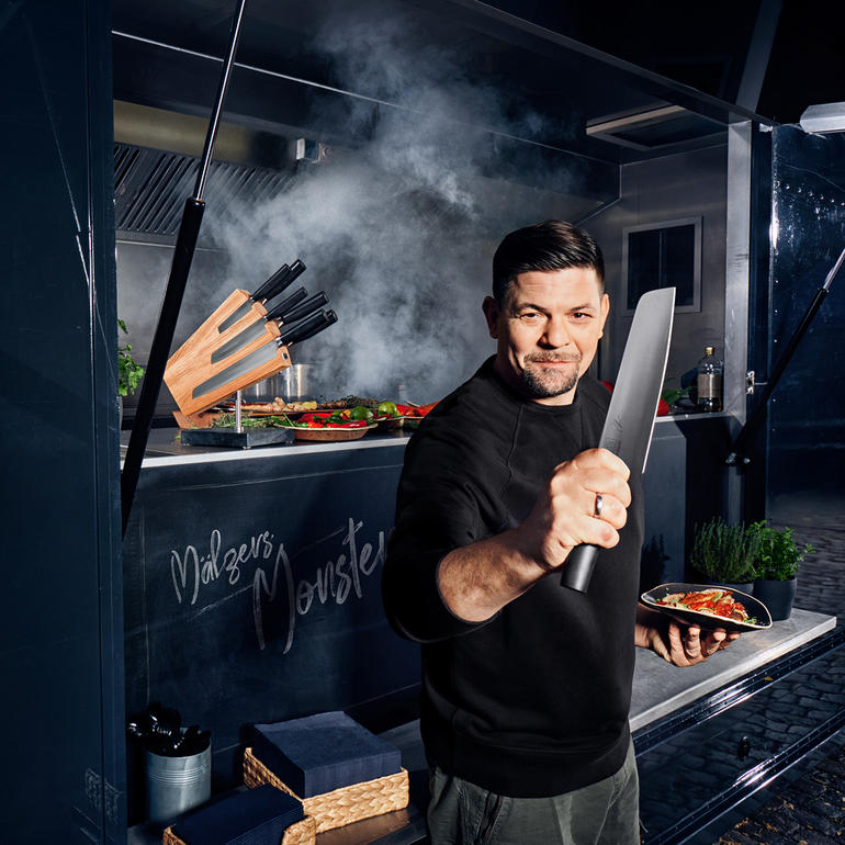 Logo und Tim Mälzer-Signatur sind sorgfältig und haltbar eingraviert. Mann mit Kamagata-Messer in der Hand in einem Foodtruck.