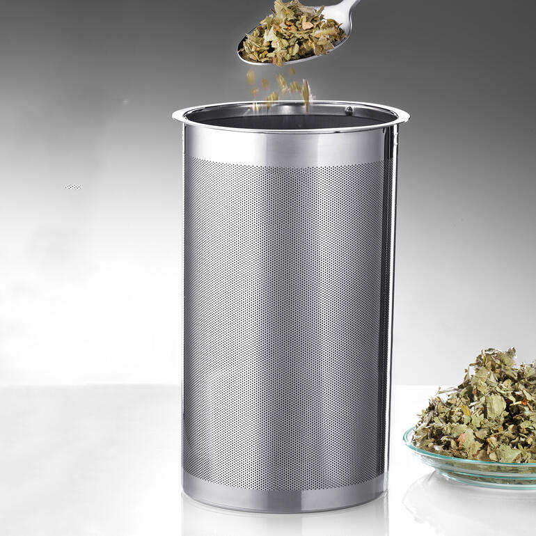 Der doppelte Mikrofilter aus Edelstahl ist fein genug sogar für losen Blatttee. Edelstahlfilter für die Kaffeebereitung mit Tee auf einem Teller.
