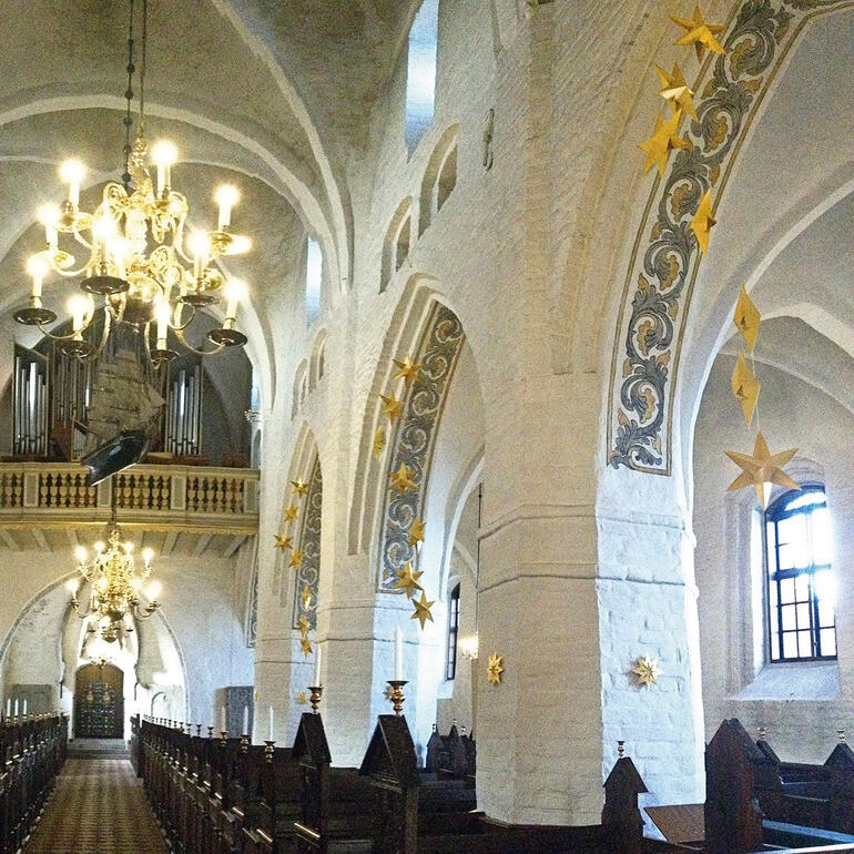 Goldfarbener Mobiler Sternentanz in einer Kirche mit vielen hängenden Sternen.