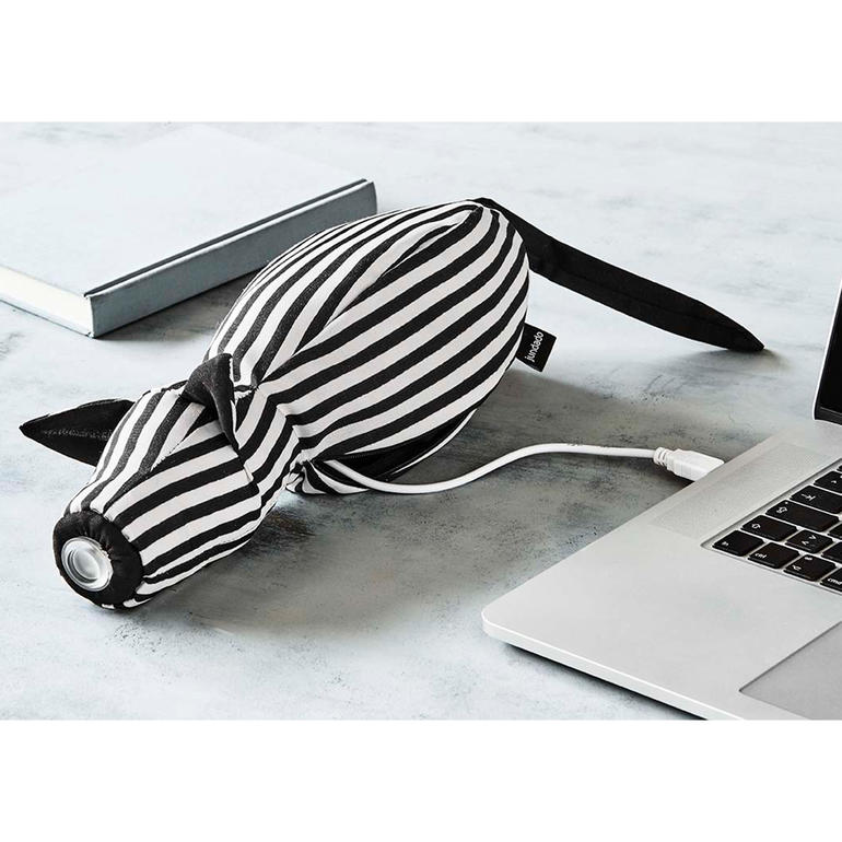 Einfach per USB-Ladekabel (mitgeliefert) aufzuladen. Leseleuchte in Tierform mit Streifenmuster, auf einem Tisch mit Laptop und Buch.