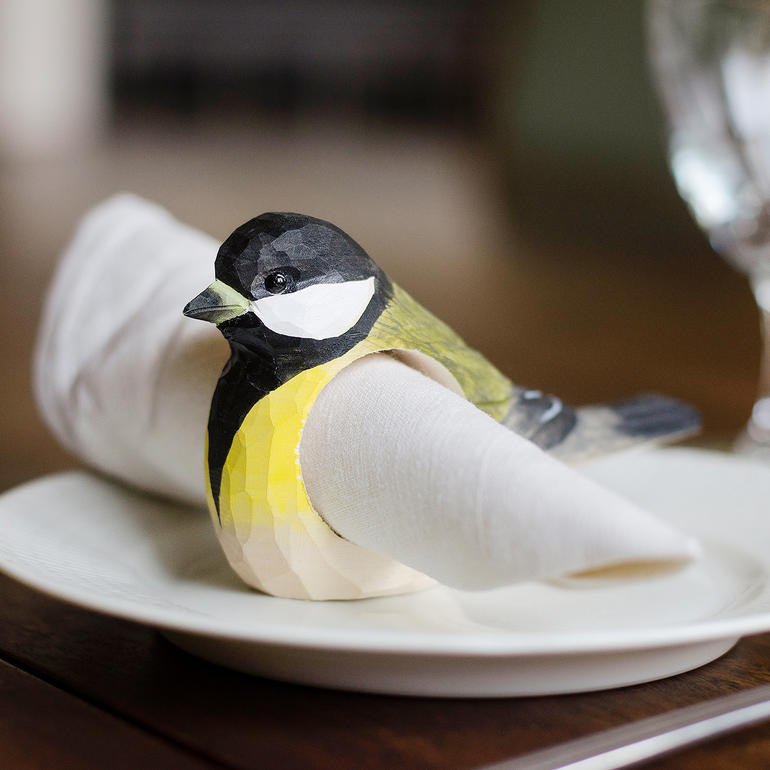 Bunter Serviettenring in Form eines Vogels auf einem weißen Teller mit einer Serviette.