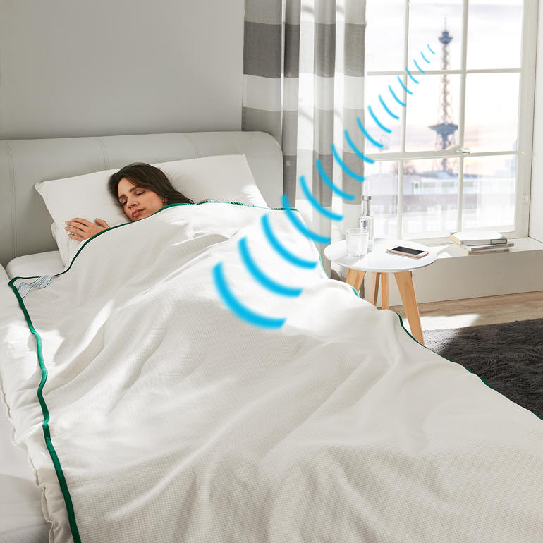 Frau schläft unter der Sleep Safe® Abschirmdecke in einem modernen Schlafzimmer.