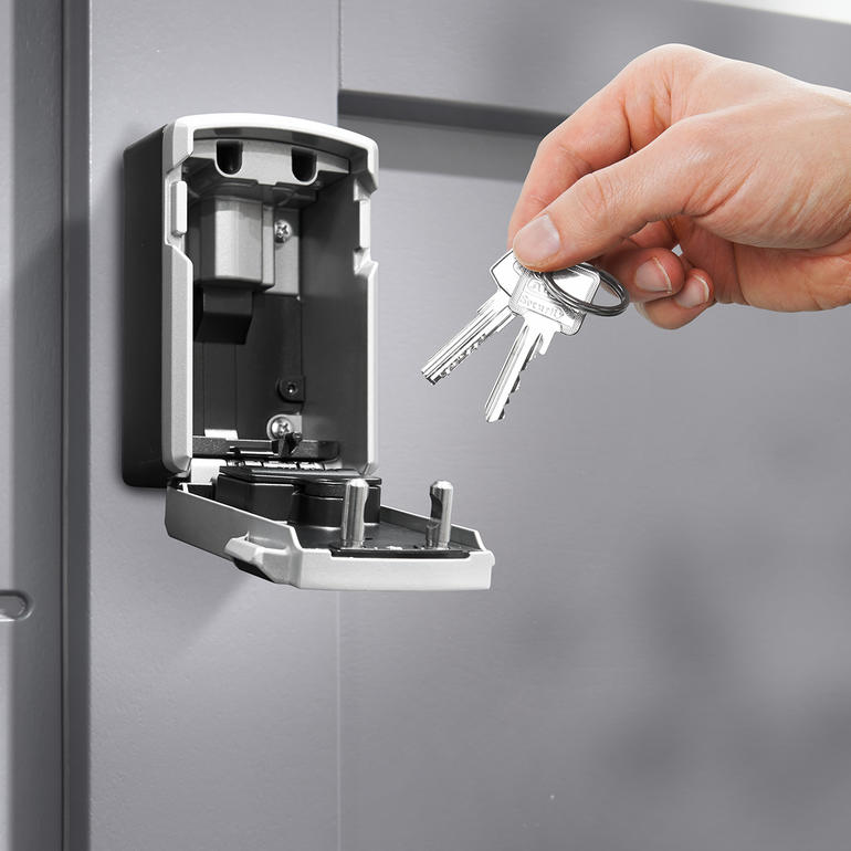 Platz für mehrere Ihrer Schlüssel und/oder Zugangskarten. Hand nimmt Schlüssel aus einem elektronischen Schlüsseltresor.
