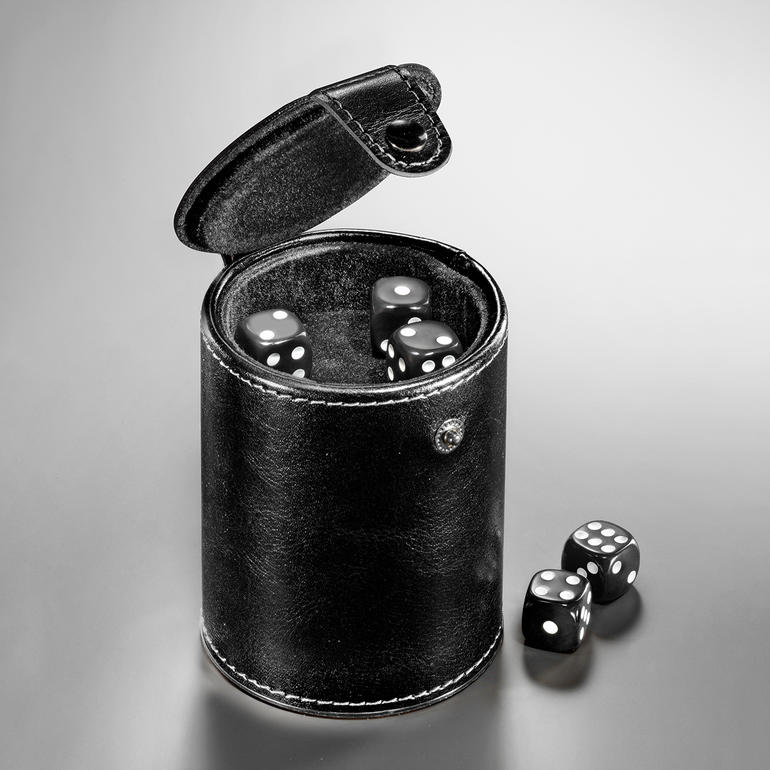 Besonders praktisch: das integrierte Würfelfach im Becherboden. Schwarzer Würfelbecher mit geöffnetem Deckel und schwarzen Würfeln.