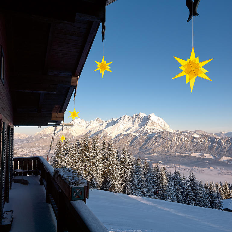 Cazador-del-sol® Sonnenfänger-Sterne Gelbe Sterne hängen an einem Balkon mit Berglandschaft im Hintergrund