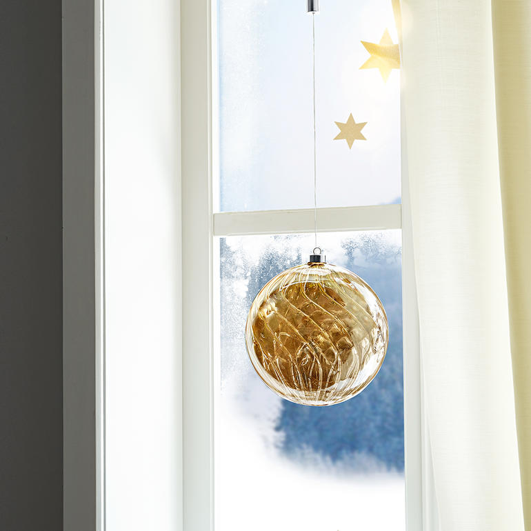 Getönte Glaskugel mit Mikro-LEDs hängt am Fenster