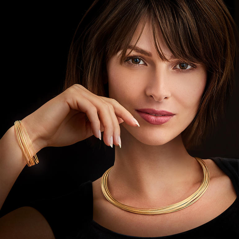 10-reihiges Gold-Armband oder 20-reihiges Gold-Collier Frau mit Gold-Armband und Gold-Collier, lächelt in die Kamera