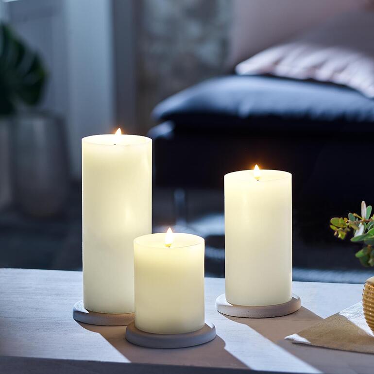 Set von drei LED-Kerzen in verschiedenen Höhen auf einem Tisch.