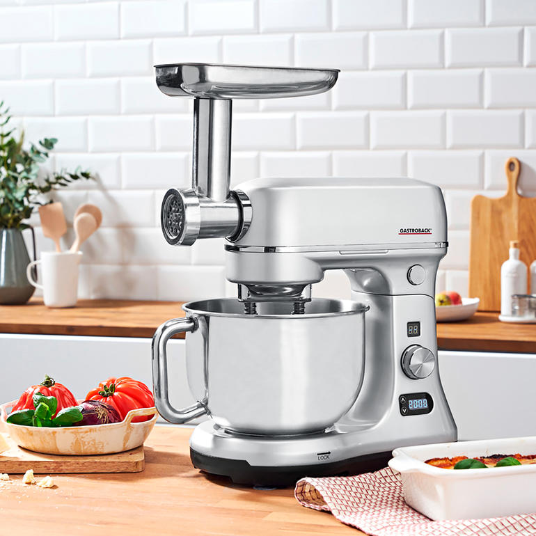 Mit umfangreichem Aufsatz-Set zur Herstellung von Spritzgebäck, verschiedenen Pasta-Sorten, Wurst und Kebab. Gastroback Küchenmaschine Advanced Digital auf Holzarbeitsplatte mit Schüssel und Aufsatz.