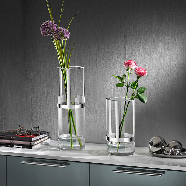 Zwei höhenverstellbare Vasen mit frischen Blumen auf einem Tisch.