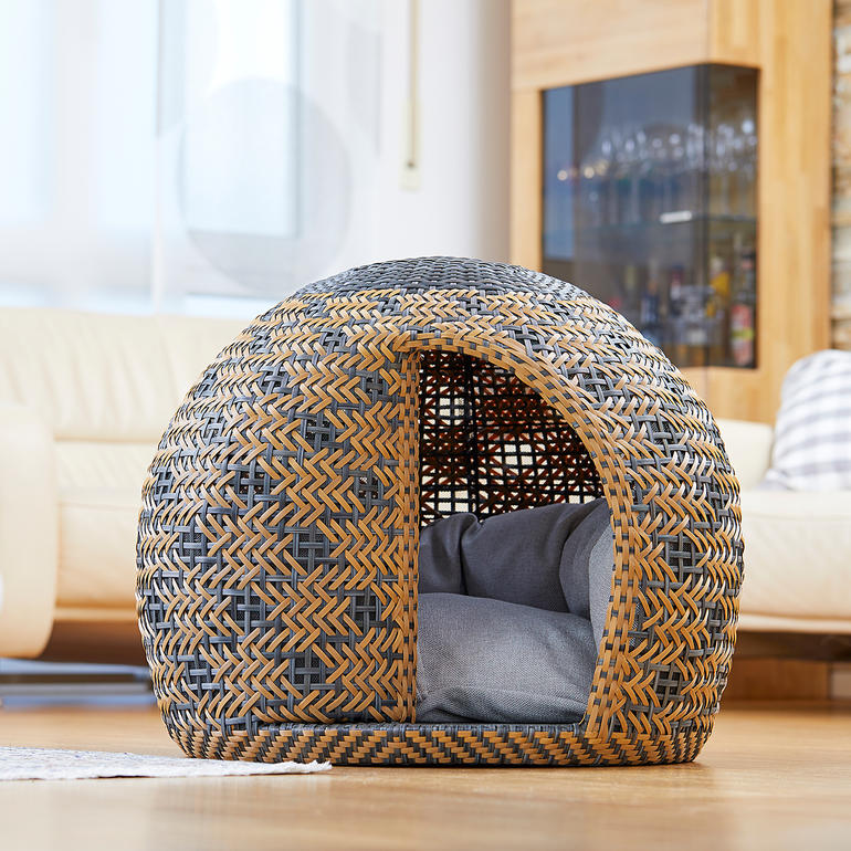 Rundes Tierhaus aus geflochtenem Material mit Kissen im Inneren.