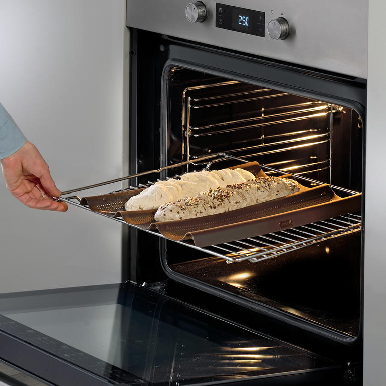 Mit dieser vorgeformten Silikon-Backmatte gelingen rundum knusprig gebackene Baguettes perfekt. Silikon Baguette-Backmatte wird aus dem Ofen genommen.
