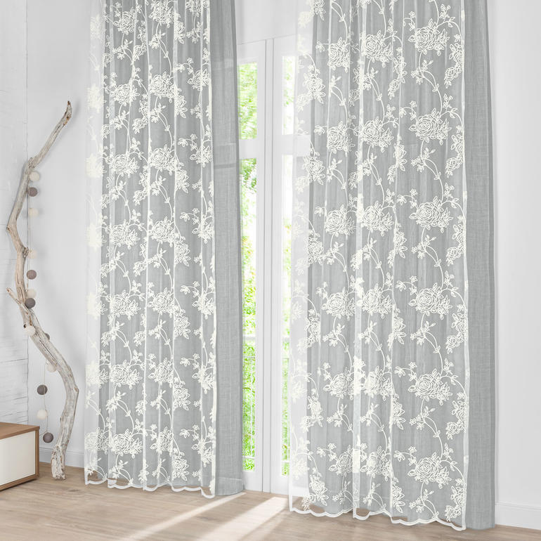 Grau gefärbter Vorhang Amari mit floralen Details im Wohnzimmer.