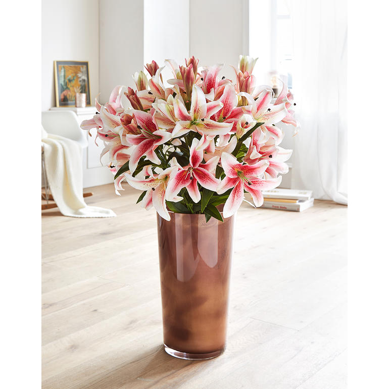 Rosé Lilienstrauß in einer kräftigen Vase im Wohnzimmer.