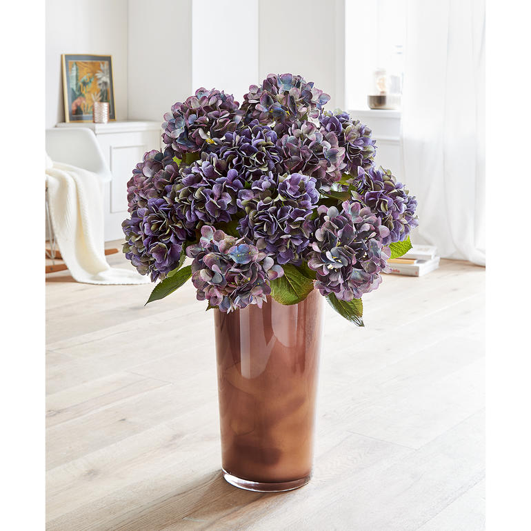 Ein bezauberndes Composé, das mit allen hellen und dunklen Wohnfarben harmoniert. Bunte Hortensie im Blumenstrauß in einer transparenten Vase.
