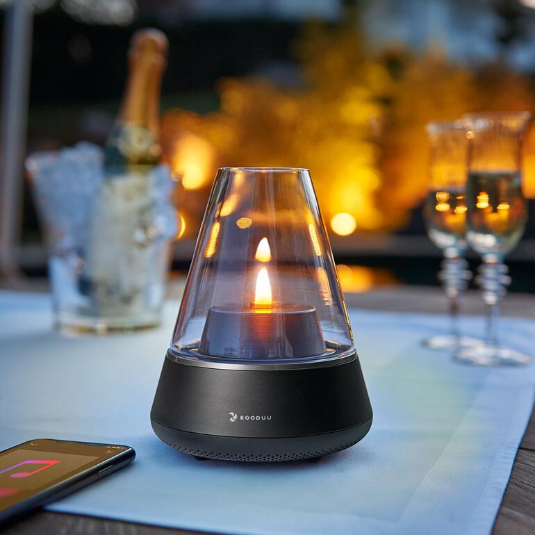 Soundlight Nordic mit brennender Kerze auf einem Tisch im Freien.